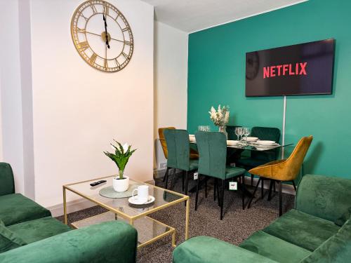 a living room with a table and a clock on the wall at Hambledon House 4BR Entire Home in Middlesbrough
