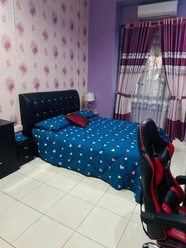 a bedroom with a bed with a blue comforter and a chair at Homestay Bukit Katil Damai 2 in Ayer Keroh