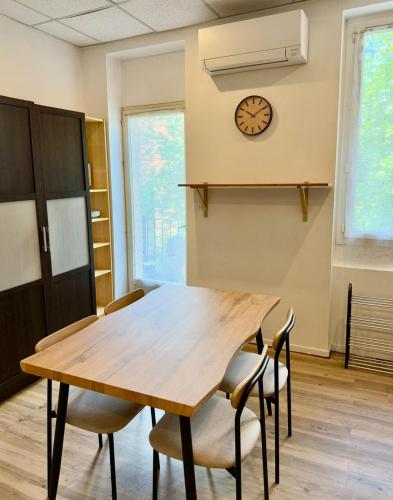 une table et des chaises dans une pièce avec une horloge au mur dans l'établissement Appartement Gare Toulouse Matabiau Climatisé, à Toulouse