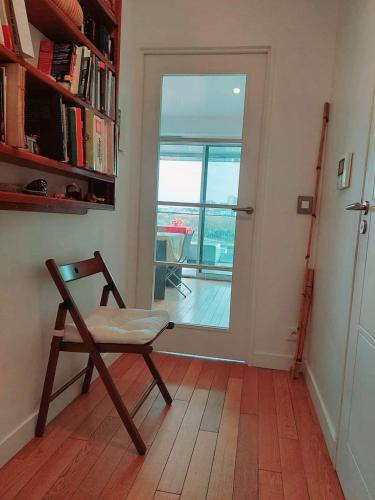 Cette chambre dispose d'une chaise et d'une porte avec un balcon. dans l'établissement Cozy and Modern Studio in Greater Paris, à Boulogne-Billancourt