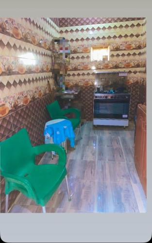 a room with three green chairs and a stove at Nubian night in Jazīrat Suhayl
