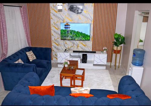 a living room with two blue couches and a piano at Chiq 1 bedroom for short and long stay accomodation - Ruiru Astrol Apartments in Ruiru
