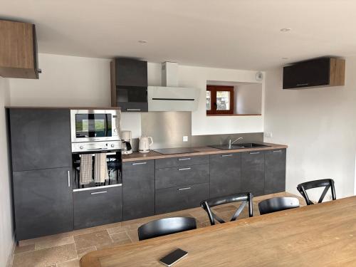 a kitchen with a table and chairs and a microwave at 2 gîtes à la campagne, proche mer, 18 personnes in Landévant