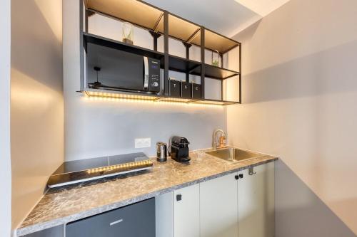 une cuisine avec un évier et un micro-ondes dans l'établissement Charmant Studio 15 minutes from Paris, à Rosny-sous-Bois