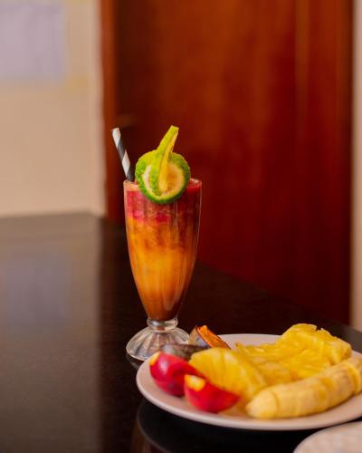 Rond Point Gorilla Boutique and Apartments في Ruhengeri: مشروب على طاولة بجانب صحن من الفاكهة