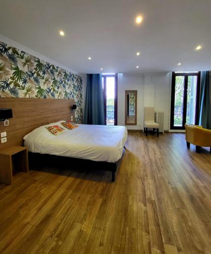 a bedroom with a large bed and wooden floors at Le Grand Hôtel Molière in Pézenas