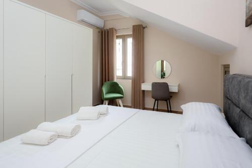 a bedroom with a white bed and a green chair at Saliasi hotel&apartament in Poliçan