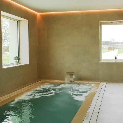 a large swimming pool in a room with two windows at Masseria Surace in Noci