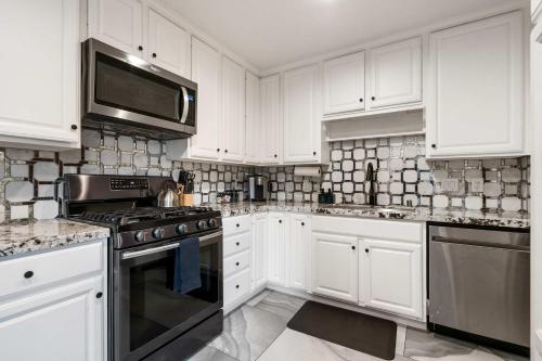 a kitchen with white cabinets and a stove top oven at San Diego Chill House with Jacuzzi-Golf-Game Room in San Diego