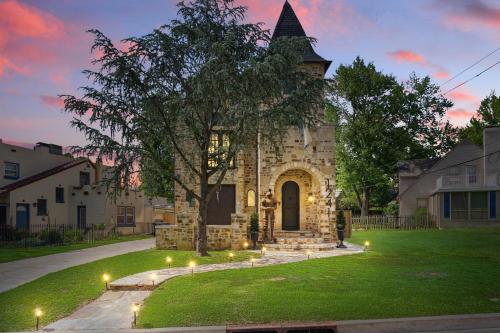 a stone building with a tree in the yard at Castle Stay by Gathering Place Hot Tub & Fire Pit in Tulsa