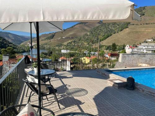 a patio with a table and an umbrella next to a swimming pool at Casa Nunes in Pinhão