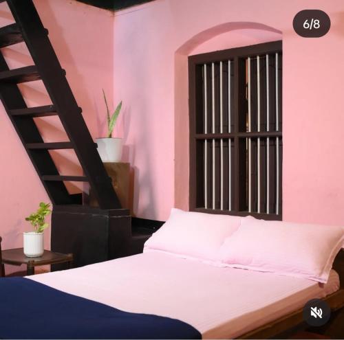 a pink room with a bed and a ladder at Coffeeisland vintage stay in Meenangadi