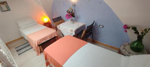 a room with two beds and a table with a vase of flowers at Dimora Maltese in Morciano di Leuca