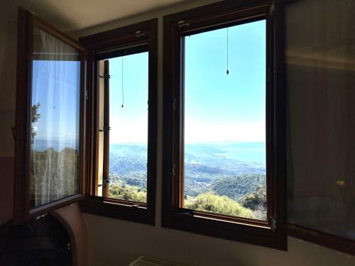 three windows in a room with a view of the mountains at RASTONI Pelion in Vizitsa