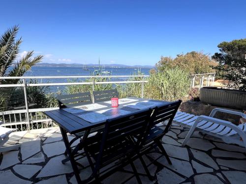 stół i krzesła na tarasie z widokiem na wodę w obiekcie La Madrague Waterfront Cottage w Hyères
