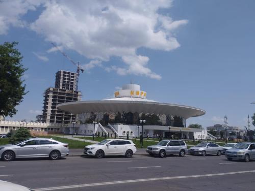 a parking lot with cars parked in front of a building at Уютный уголок Фрунзе in Bishkek