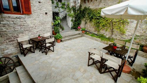 a patio with tables and chairs and an umbrella at The Home of Diplomacy in Gjirokastër