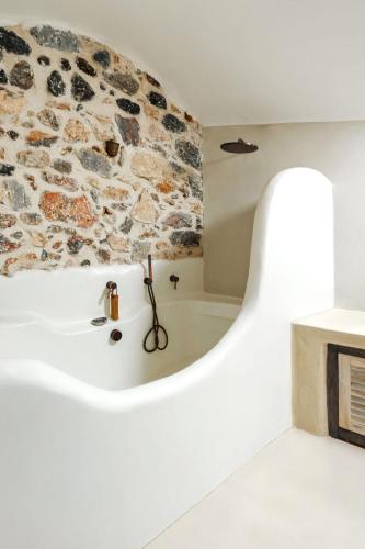 a bath tub in a bathroom with a stone wall at Santorini Vista Legacy Retreat - Live the history, wake to the view in Pirgos