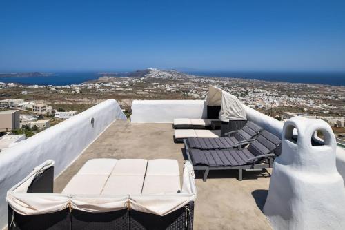 a balcony with chairs and a view of the city at Santorini Vista Legacy Retreat - Live the history, wake to the view in Pirgos