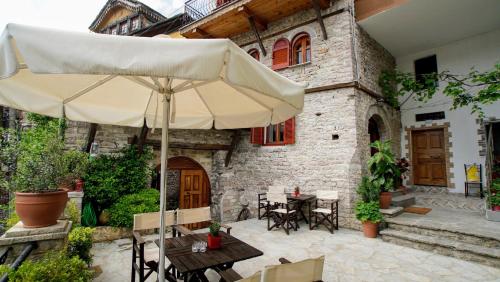 a patio with an umbrella and tables and chairs at The Home of Diplomacy in Gjirokastër