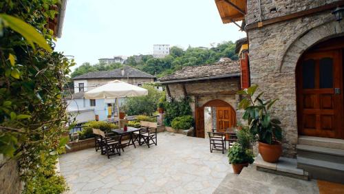 an outdoor patio with tables and chairs and an umbrella at The Home of Diplomacy in Gjirokastër