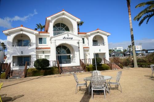 a house with a table and chairs in front of it at Jennyville Pension in Seogwipo