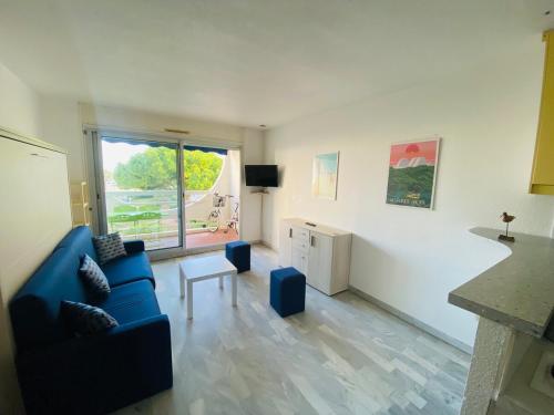 a living room with a blue couch and a table at Centre ville, studio vue port, avec parking privé in La Grande-Motte