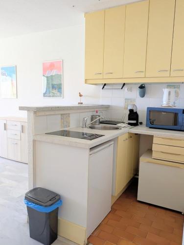une cuisine avec un évier et un micro-ondes dans l'établissement Centre ville, studio vue port, avec parking privé, à La Grande Motte