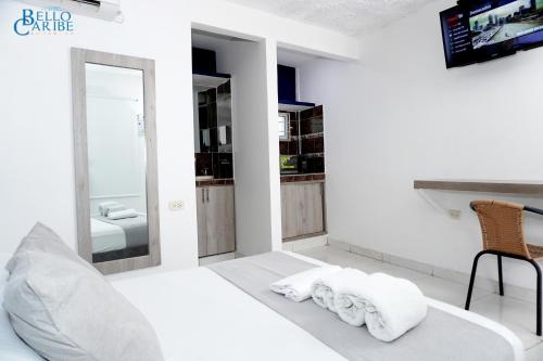 a white bedroom with a bed and a mirror at Hotel Bello Caribe Rodadero in Santa Marta