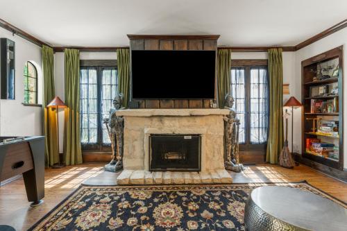 a living room with a fireplace with a flat screen tv at Castle Stay by Gathering Place Hot Tub & Fire Pit in Tulsa