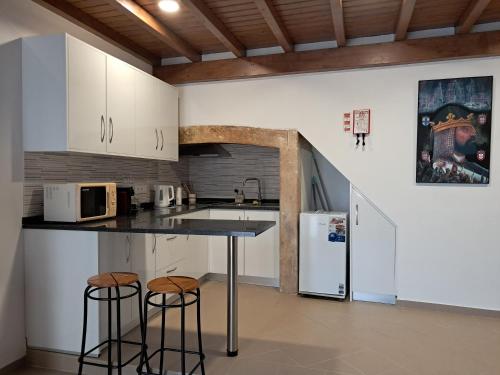 a kitchen with white cabinets and a counter and stools at Casa do Mestre in Tomar