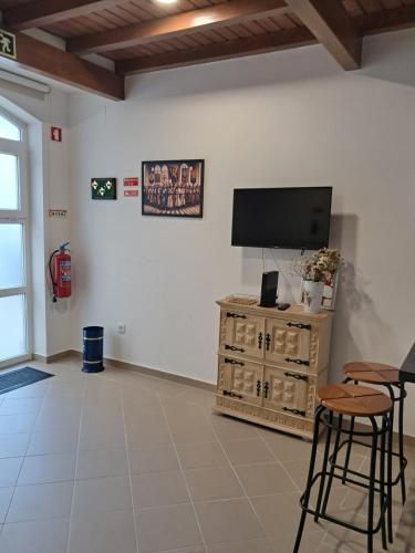 a living room with a flat screen tv and stools at Casa do Mestre in Tomar