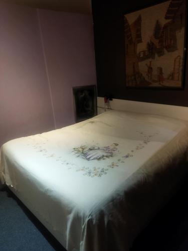 a bed with a white sheet with a picture on it at Loft 70 in Montescudaio