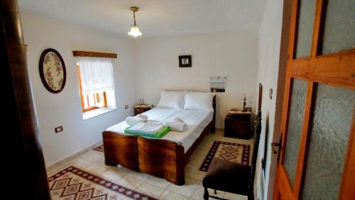 a bedroom with a bed with white sheets and a window at The Home of Diplomacy in Gjirokastër