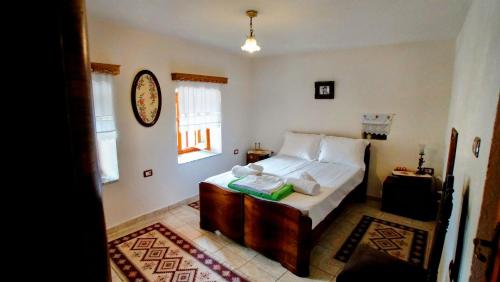 a bedroom with a bed with white sheets and a window at The Home of Diplomacy in Gjirokastër