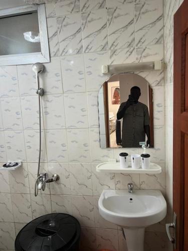 a man taking a picture of a bathroom with a sink at Lekker Estate in Yaoundé