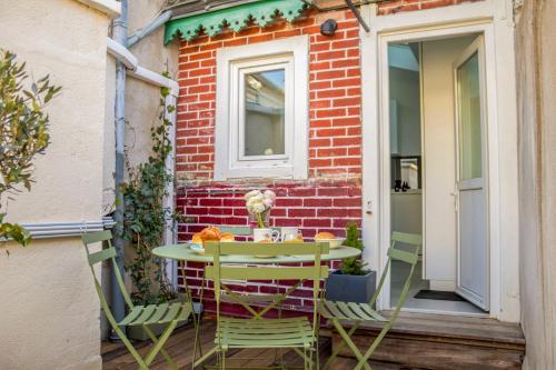 une table et des chaises assises sur une terrasse dans l'établissement Le Patio des Arts - Parking - By PrestiPlace, à Tours
