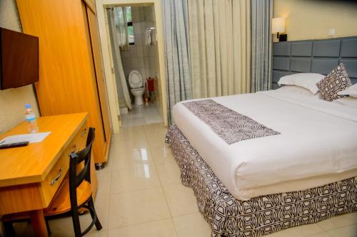 a hotel room with a bed and a desk and a bathroom at Quality Inn Hotel Kigali in Kigali