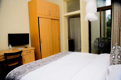 a bedroom with a bed and a desk with a television at Quality Inn Hotel Kigali in Kigali