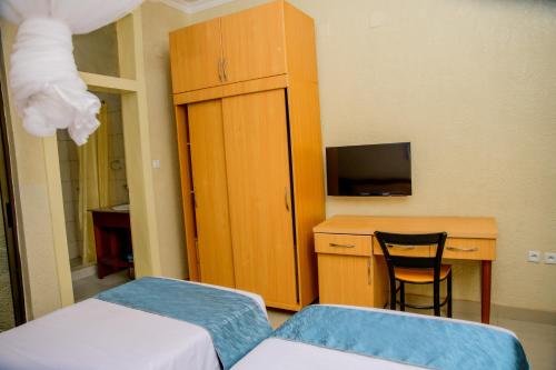 a room with two beds and a desk and a cabinet at Quality Inn Hotel Kigali in Kigali