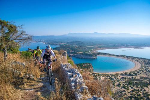 two people riding bikes on a hill near a lake at The Westin Resort, Costa Navarino in Romanós