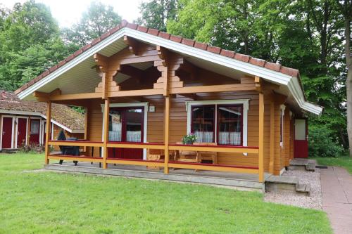 a small wooden house with a porch at Juromi 42 in Gramsbergen