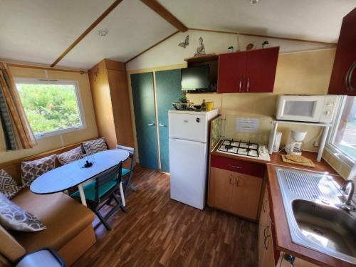 une petite cuisine avec une table et un réfrigérateur dans l'établissement MOBIL HOME DANS CAMPING 3 etoiles GORGES DU VERDON CALME 4 PERS PLANCHA, à Sainte-Croix-de-Verdon