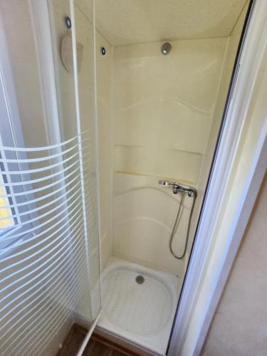 une douche avec une porte vitrée dans une salle de bain dans l'établissement MOBIL HOME DANS CAMPING 3 etoiles GORGES DU VERDON CALME 4 PERS PLANCHA, à Sainte-Croix-de-Verdon