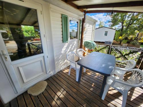 Un porche con una mesa y sillas azules. en MOBIL HOME DANS CAMPING 3 etoiles GORGES DU VERDON CALME 4 PERS PLANCHA, en Sainte-Croix-du-Verdon