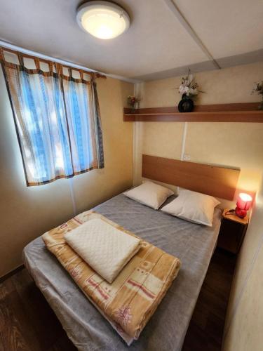 un petit lit dans une chambre avec une fenêtre dans l'établissement MOBIL HOME DANS CAMPING 3 etoiles GORGES DU VERDON CALME 4 PERS PLANCHA, à Sainte-Croix-de-Verdon