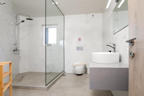a white bathroom with a sink and a shower at Anele Luxury Suites - Roof Top Jacuzzi in Chania Town