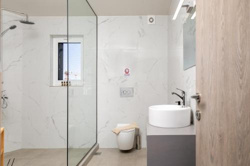 a bathroom with a sink and a glass shower at Anele Luxury Suites - Roof Top Jacuzzi in Chania Town