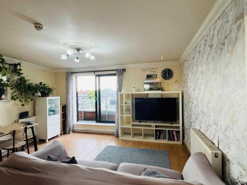 a living room with a couch and a television at Charming 2 Bedroom Flat with Urban Views in Romford