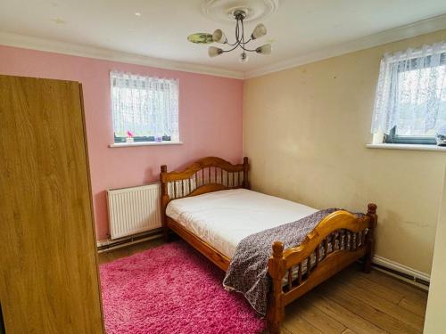 a bedroom with a bed and a pink wall at Charming 2 Bedroom Flat with Urban Views in Romford